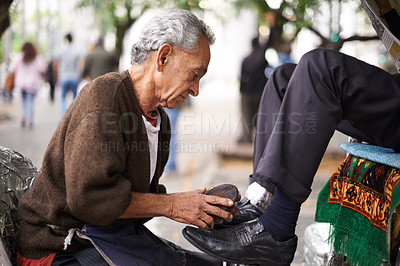 Buy stock photo Shoe cleaner, elderly man person and shining feet, small business owner and professional on busy street. Mature, senior male and experienced worker from Puerto Rico, working with brush in city 