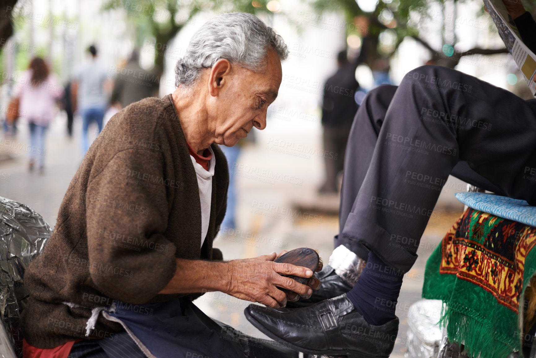 Buy stock photo Shoe cleaner, elderly man person and shining feet, small business owner and professional on busy street. Mature, senior male and experienced worker from Puerto Rico, working with brush in city 