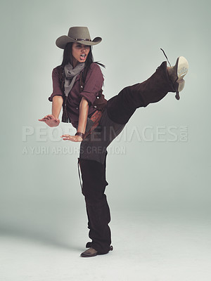 Buy stock photo Western, woman and cowboy in studio with fashion, leg up and gesture to fight on grey background. Female person, vintage and outlaw with boots for wild west, costume and character with retro hat