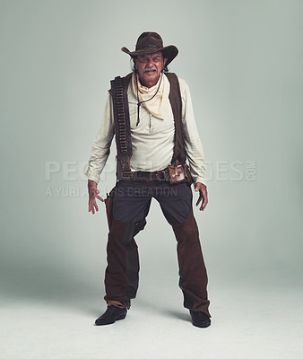 Buy stock photo A cowboy looking confrontational while isolated on gray