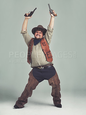 Buy stock photo An overweight cowboy looking ecstatic with his pistols in the air