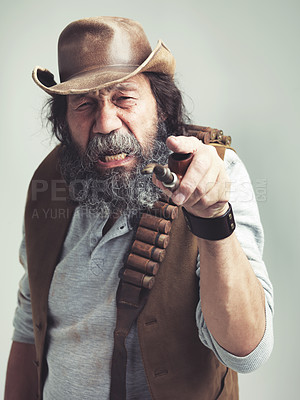 Buy stock photo Old cowboy, point and angry face at studio, costume and pipe for western portrait looking scruffy. Senior guy, upset hat and dirty male for texas, grey background and annoyed for accuse gesture