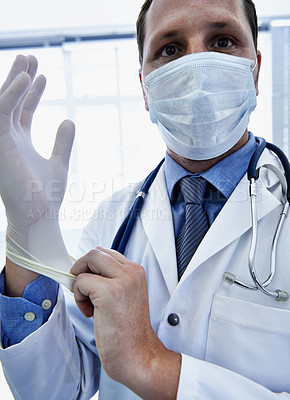 Buy stock photo Portrait, doctor and man putting on gloves for safety or protection in hospital. Face mask, medical professional or ppe to prepare for surgery, treatment or prevention of disease in healthcare clinic
