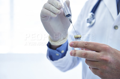 Buy stock photo Cropped shot of a male doctor filling a syringe with medicine