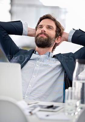 Buy stock photo Shot of a young businessman looking thoughtful while sitting at his office desk