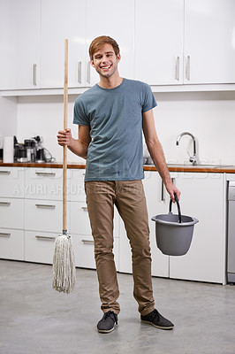 Buy stock photo Full length shot of a handsome man standing in the kitchen holding a mop and bucket