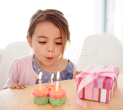 Buy stock photo Cupcakes, blowing candles and girl with birthday, child and gift with happiness, candy and home. Kid, celebration and excited with dessert or present with party or box with omg, sweet or surprise