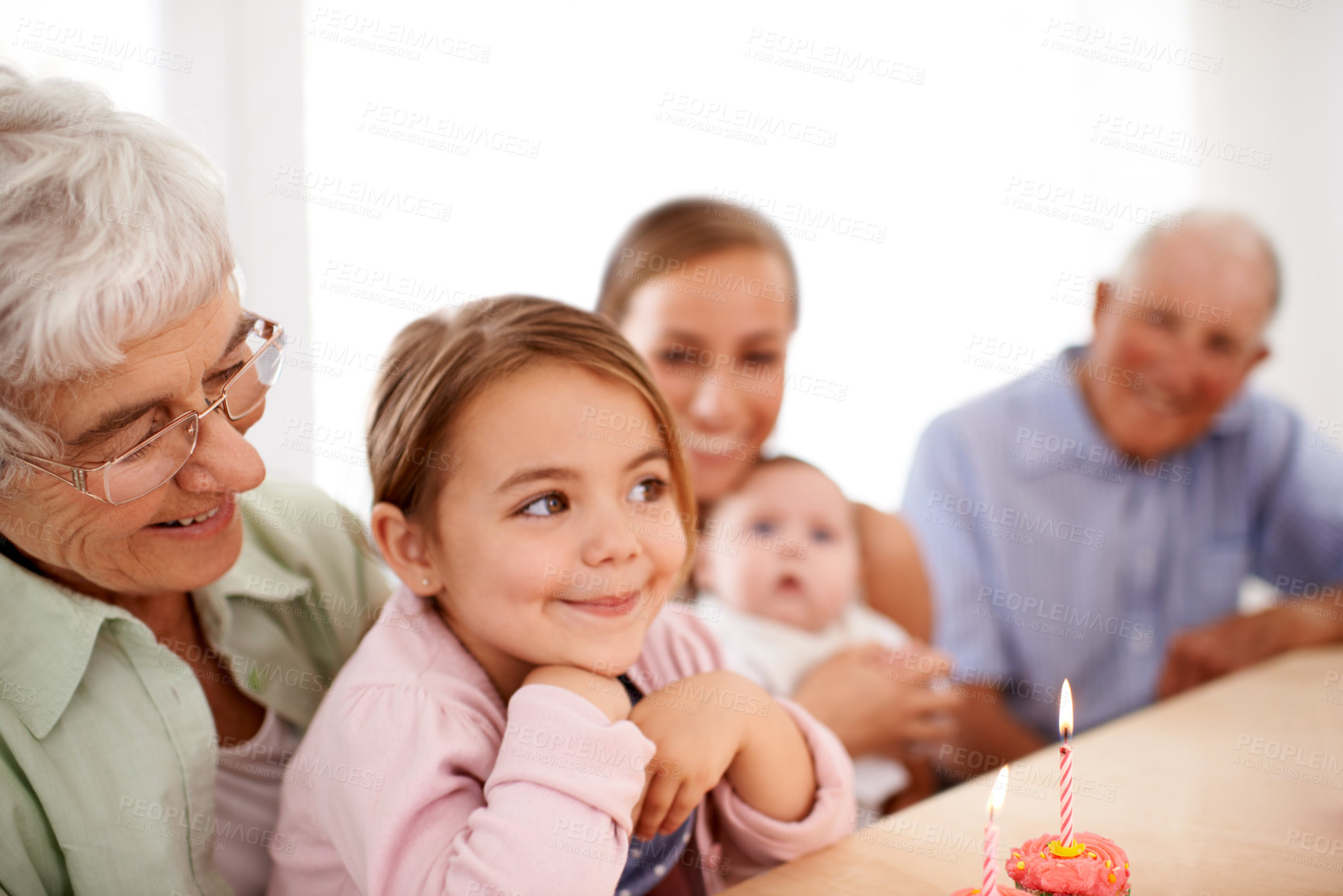 Buy stock photo Family, birthday party and cupcake with candle for celebration, mother and grandparents with children at home. Happy young girl with cake, people and smile for anniversary with dessert at event
