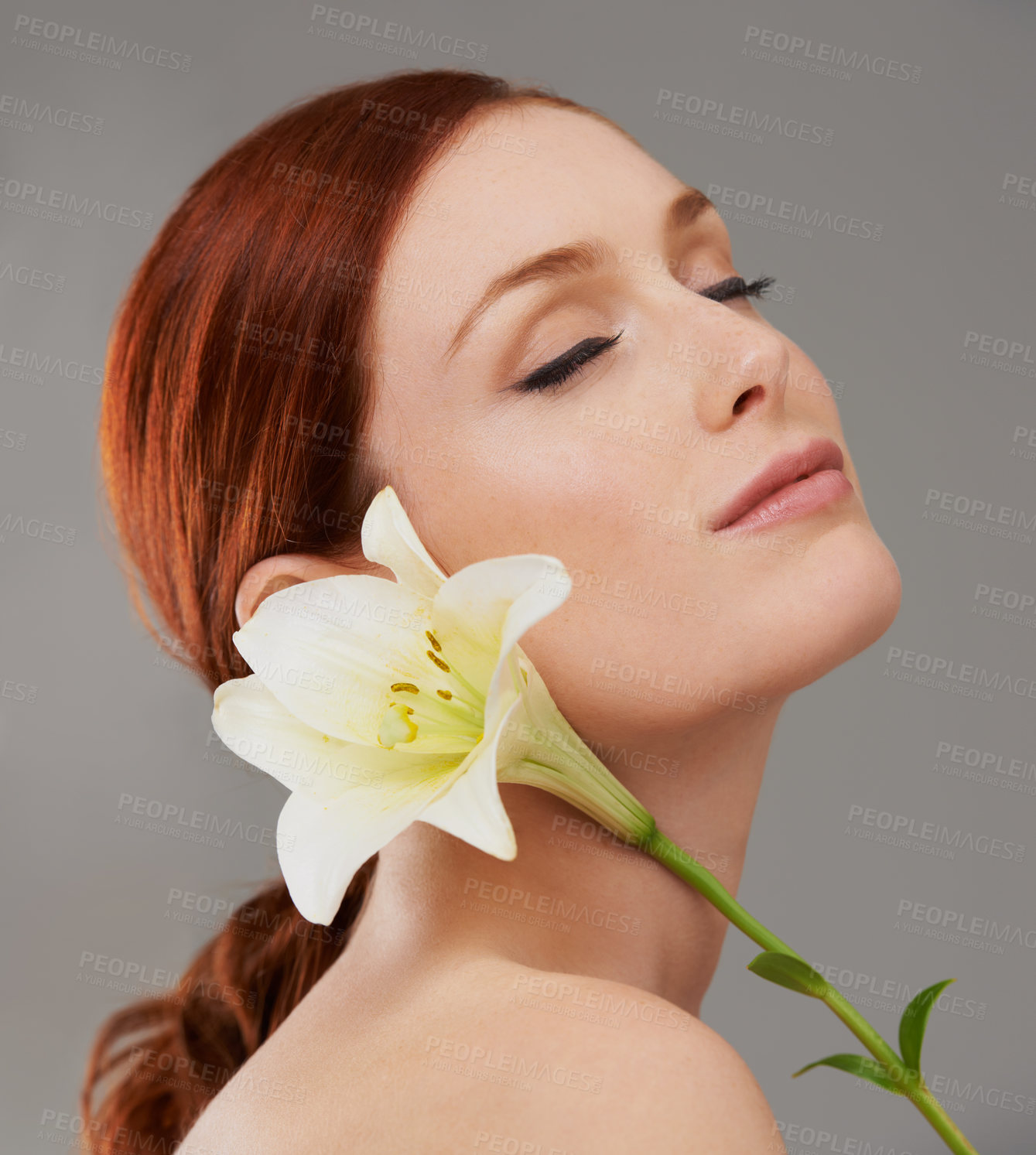 Buy stock photo Face, skincare and woman with flower, lily and natural beauty isolated on a gray studio background. Floral cosmetics, organic and model with eyes closed for glow, wellness or healthy skin with makeup