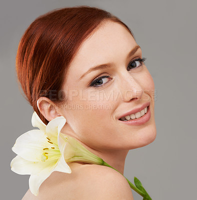 Buy stock photo Portrait, skincare and happy woman with flower, lily and natural beauty isolated on a gray studio background. Face, organic and ginger model with floral cosmetics for dermatology, wellness and makeup