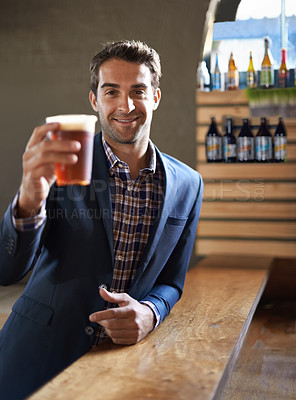 Buy stock photo Shot of a handsome young man enjoying an ale at the bar