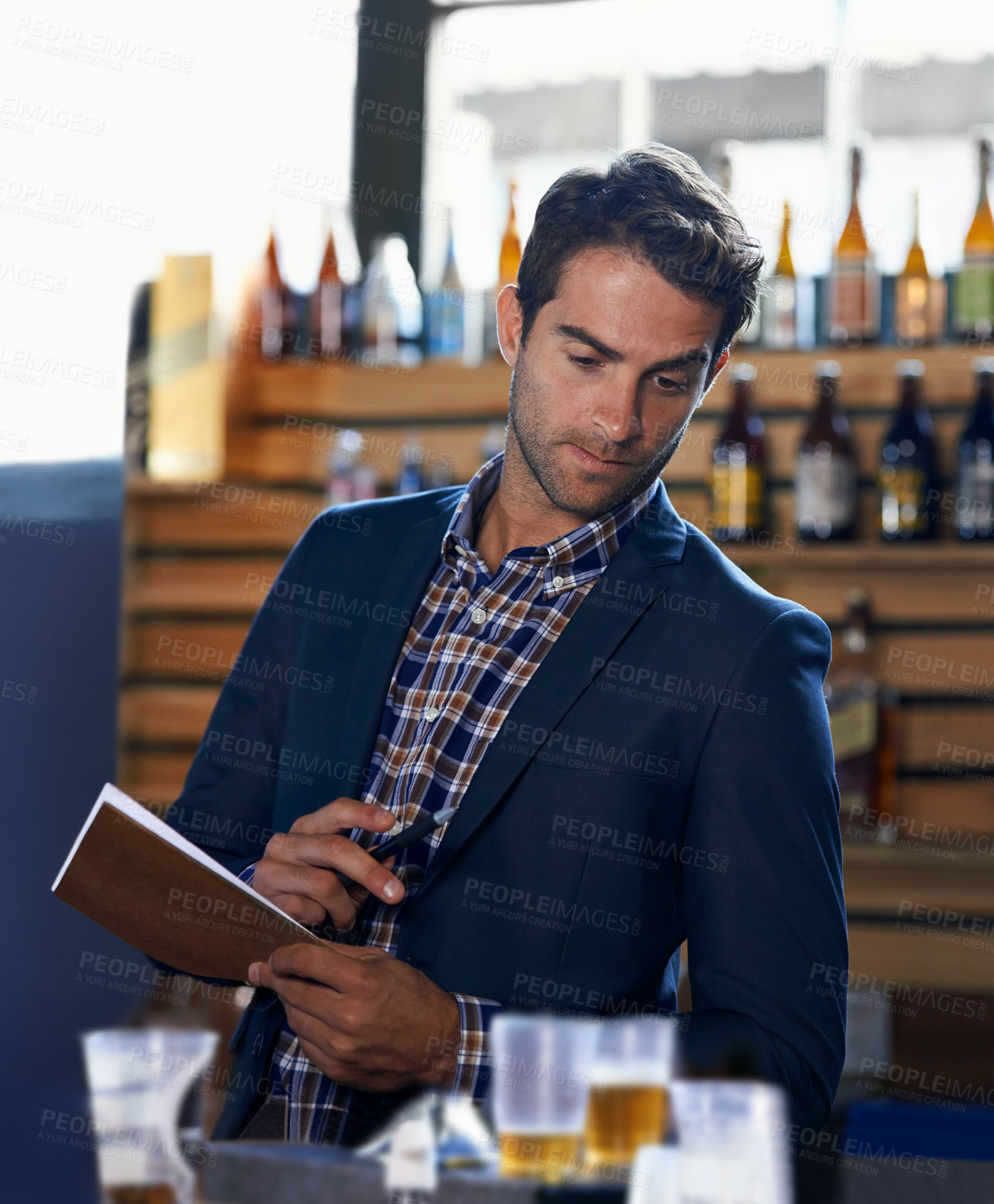Buy stock photo Shot of a handsome young man doing stock take at a bar