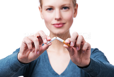 Buy stock photo A cropped studio shot of a beautiful young woman breaking a cigarette in half