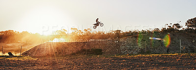 Buy stock photo Person, jump and professional motorcyclist on banner in the air for trick, stunt or ramp on outdoor dirt track. Expert rider on motorbike with lift for extreme sports or rally challenge in the sunset