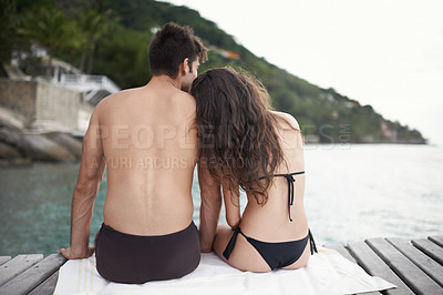 Buy stock photo Couple, jetty and travel to ocean on vacation, touch and relax by water on summer holiday. People, swimwear and bonding for relationship in outdoors, support and back on weekend trip to sea or nature
