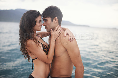 Buy stock photo Shot of an intimate young couple enjoying a vacation by the sea