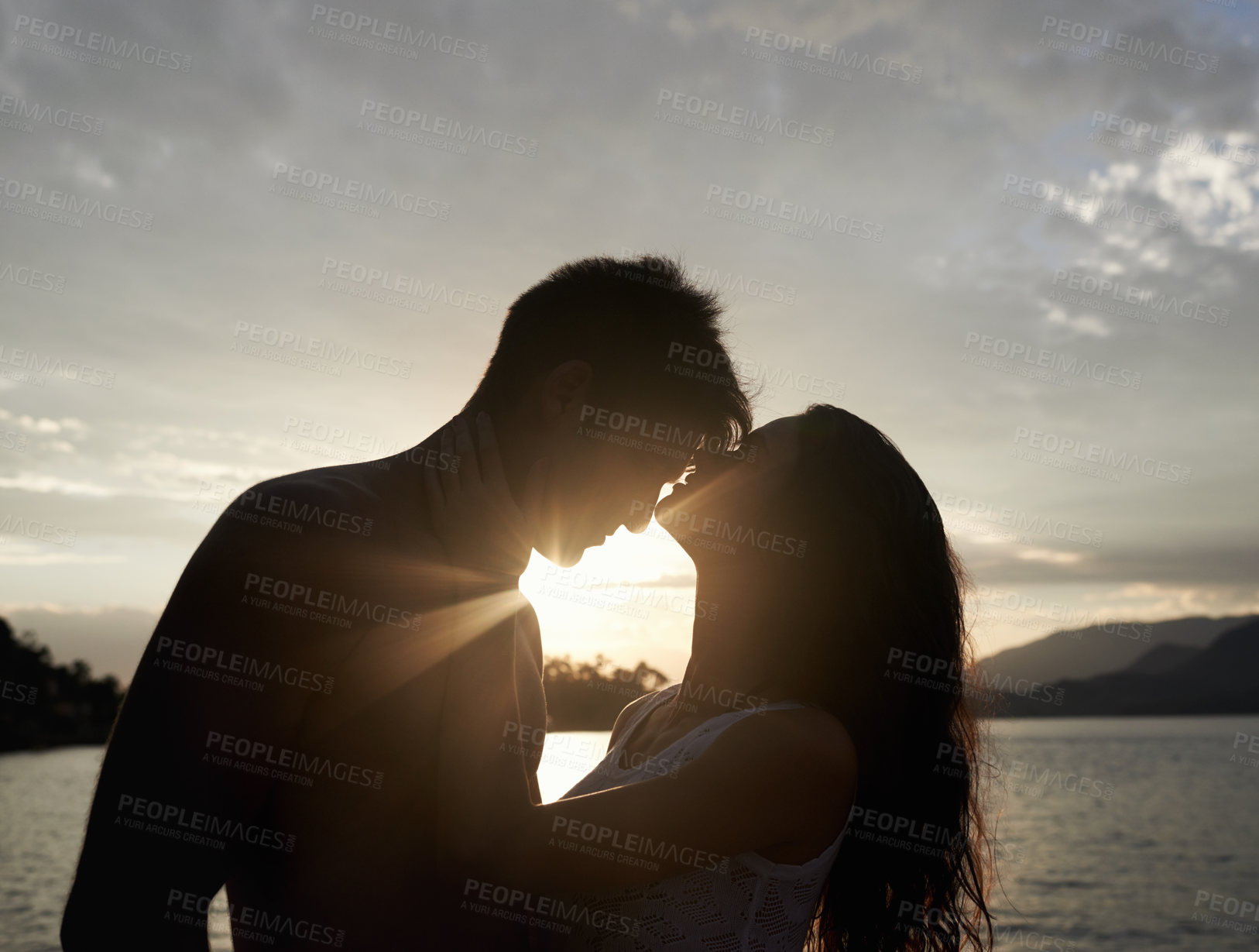 Buy stock photo Silhouette, couple and love by sea at sunset, vacation or travel together in summer. Man, woman and romance at ocean with shadow for connection, relationship and commitment by water outdoor in nature