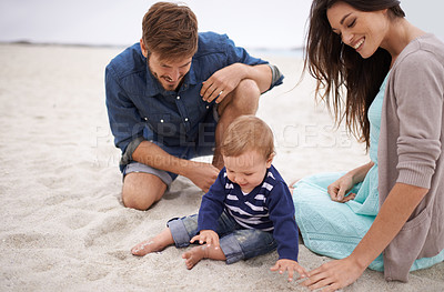 Buy stock photo Cropped shot of a young couple and their baby boy sitting on the beach