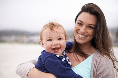 Buy stock photo Portrait of a an attractive young woman holding her baby boy at the beach
