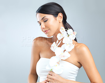 Buy stock photo Flowers, wellness and woman with dermatology, shine and person on a grey studio background. Model, luxury or girl with aesthetic or natural with facial or skincare with glow and beauty with cosmetics