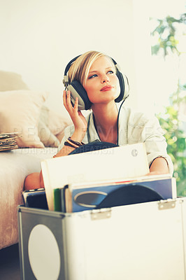 Buy stock photo A beautiful young woman listening to music while relaxing at home
