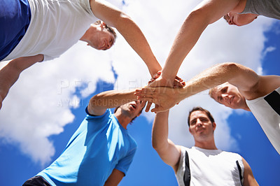 Buy stock photo Shot of a group of young sportsmen piling their hands while standing in a huddle