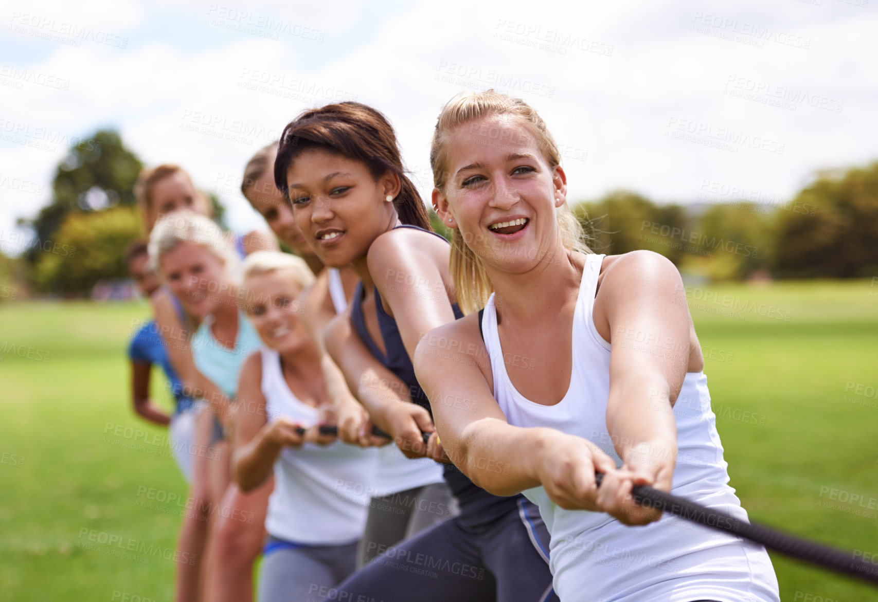 Buy stock photo Cropped shot of a girls' tug-of-war team training outdoors