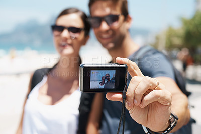 Buy stock photo Couple, beach and digital camera for selfie on holiday with smile, sunglasses and outdoor for memory in summer. People, man and woman with photography by sea for journey, vacation and screen in Italy