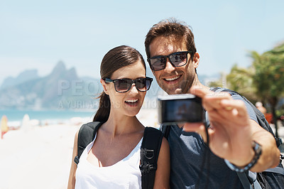 Buy stock photo Couple, beach and camera for selfie on holiday with smile, sunglasses and outdoor for memory in summer. People, man and woman with photography by ocean for journey, vacation and sunshine in Italy