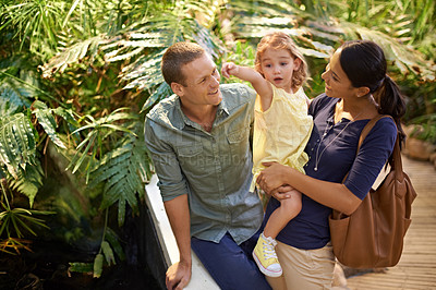 Buy stock photo Happy family, child and pointing at zoo with tourist for sightseeing, travel or tour on trip. Father, mother and little girl showing direction, guide or exhibit to explore together in outdoor nature