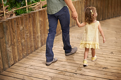 Buy stock photo Little girl, father and holding hands with parent for bonding, adventure or fun field trip. Rear view of young child or kid walking with dad for safety, protection or sightseeing together in nature