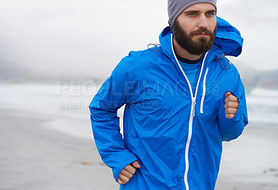 Buy stock photo Cropped shot of a handsome young man running on the beach