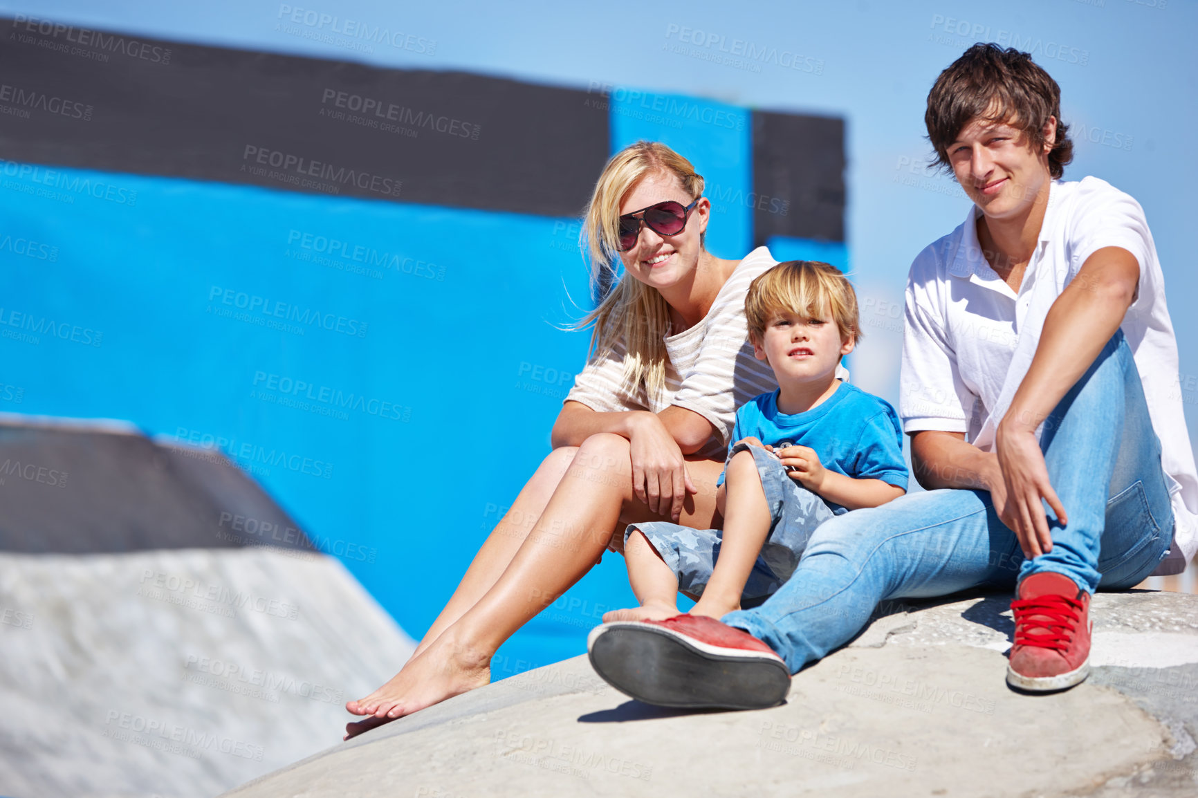 Buy stock photo Portrait of a two young teens and a little boy sitting outside at a skate park