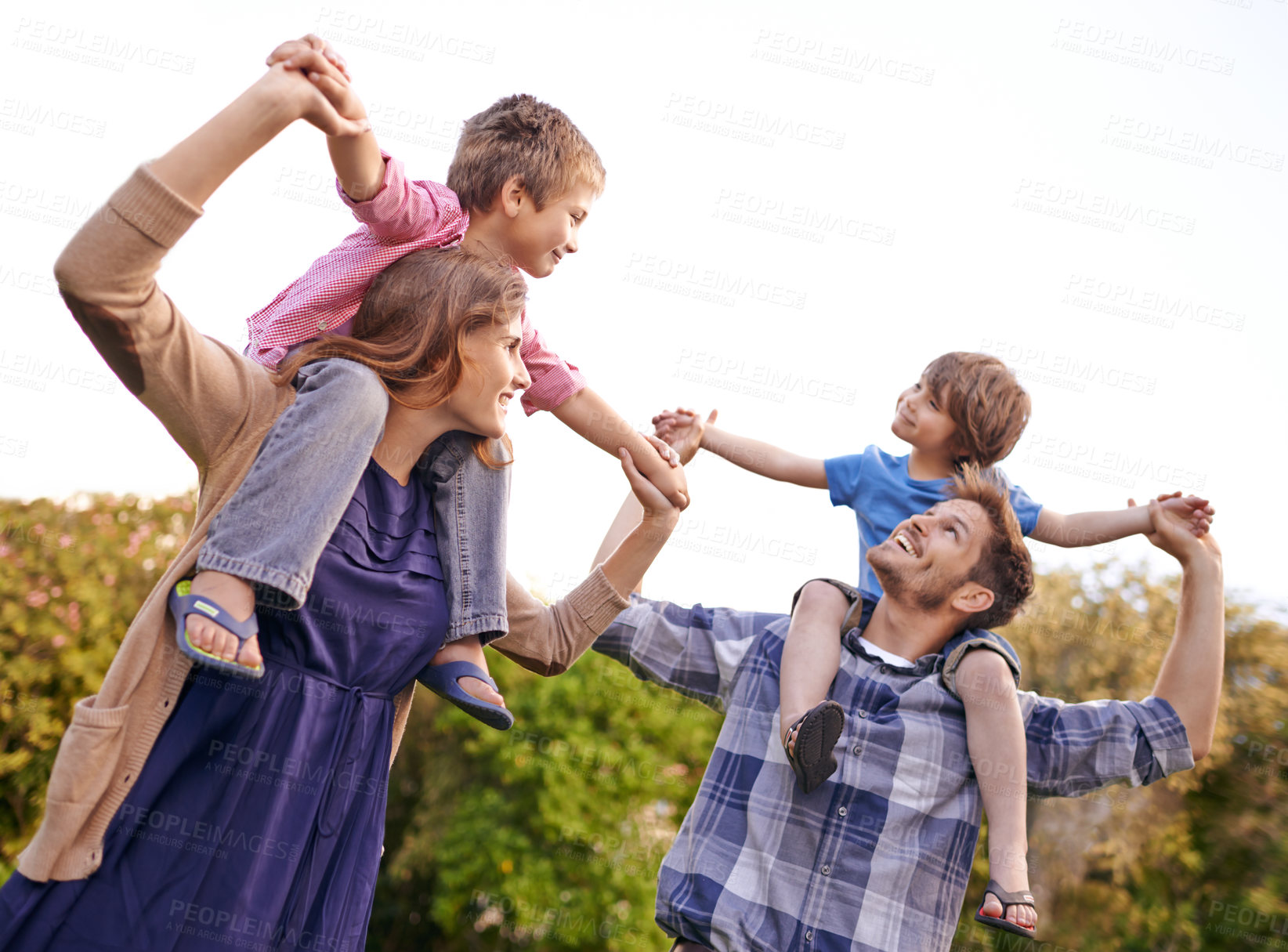 Buy stock photo Excited, nature and children on parents shoulders in outdoor park or field for playing together. Happy, bonding and young mother and father carrying boy kids for fun in garden in Canada for summer.