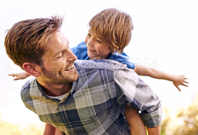 Buy stock photo Cropped shot of a young father giving his son a piggyback ride