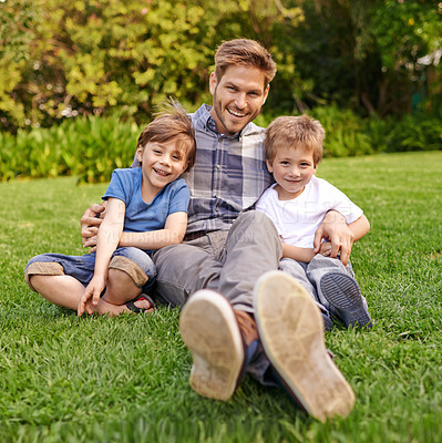 Buy stock photo Smile, nature and portrait of children with father relaxing on grass in outdoor park or garden. Happy, family and excited cute boy kids sitting on lawn with young dad for bonding in field together.