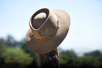 Buy stock photo Cowboy hat, outdoor and wood post for protection from sun with fashion at ranch, countryside and nature. Vintage cap, headwear and shade from sunshine with farming, agriculture and summer in Texas