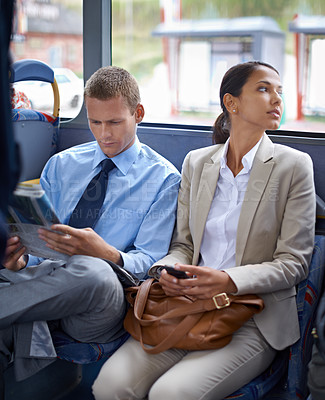 Buy stock photo Business people, man and woman on bus for public transport, newspaper and smartphone for urban commute. Professional, colleagues and coworkers in transit or traveling to work in formal clothes