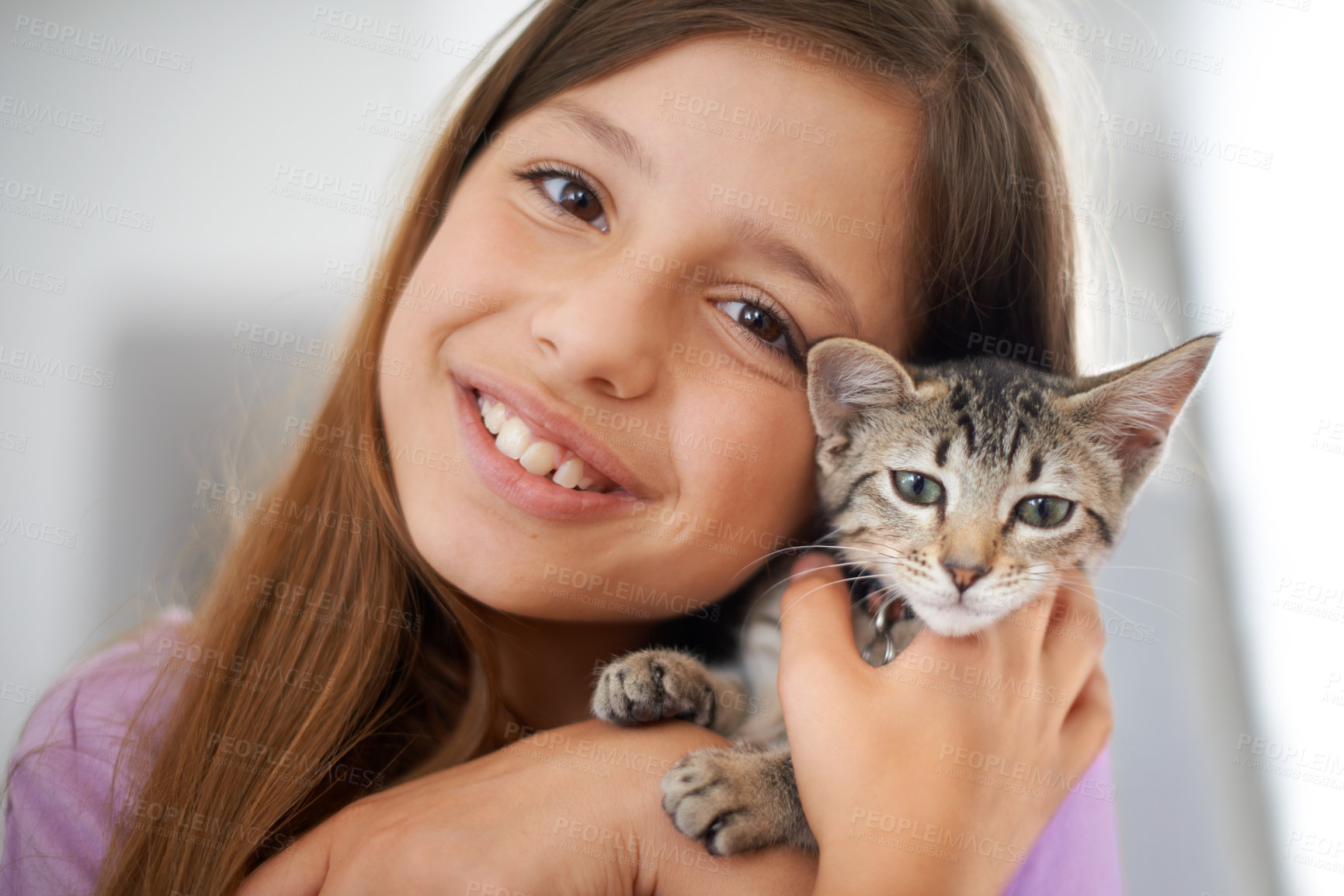 Buy stock photo A happy young girl holding a kitten affectionately