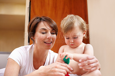 Buy stock photo A mother showing her baby girl a colorful spoon