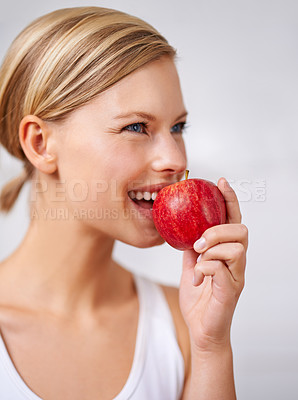 Buy stock photo A cropped shot of a beautiful young woman eating a delicious red apple