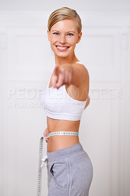 Buy stock photo A portrait of a beautiful young woman measuring her waist and pointing