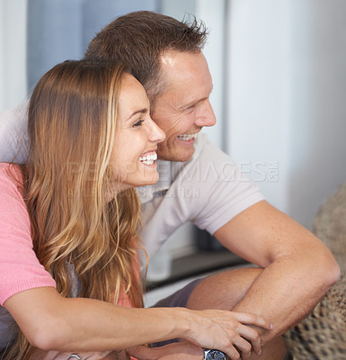 Buy stock photo Love, man and woman in living room with smile on face, relax and bonding with free time on weekend in apartment. Profile, embrace and happy couple in home with trust, fun and romance in marriage.