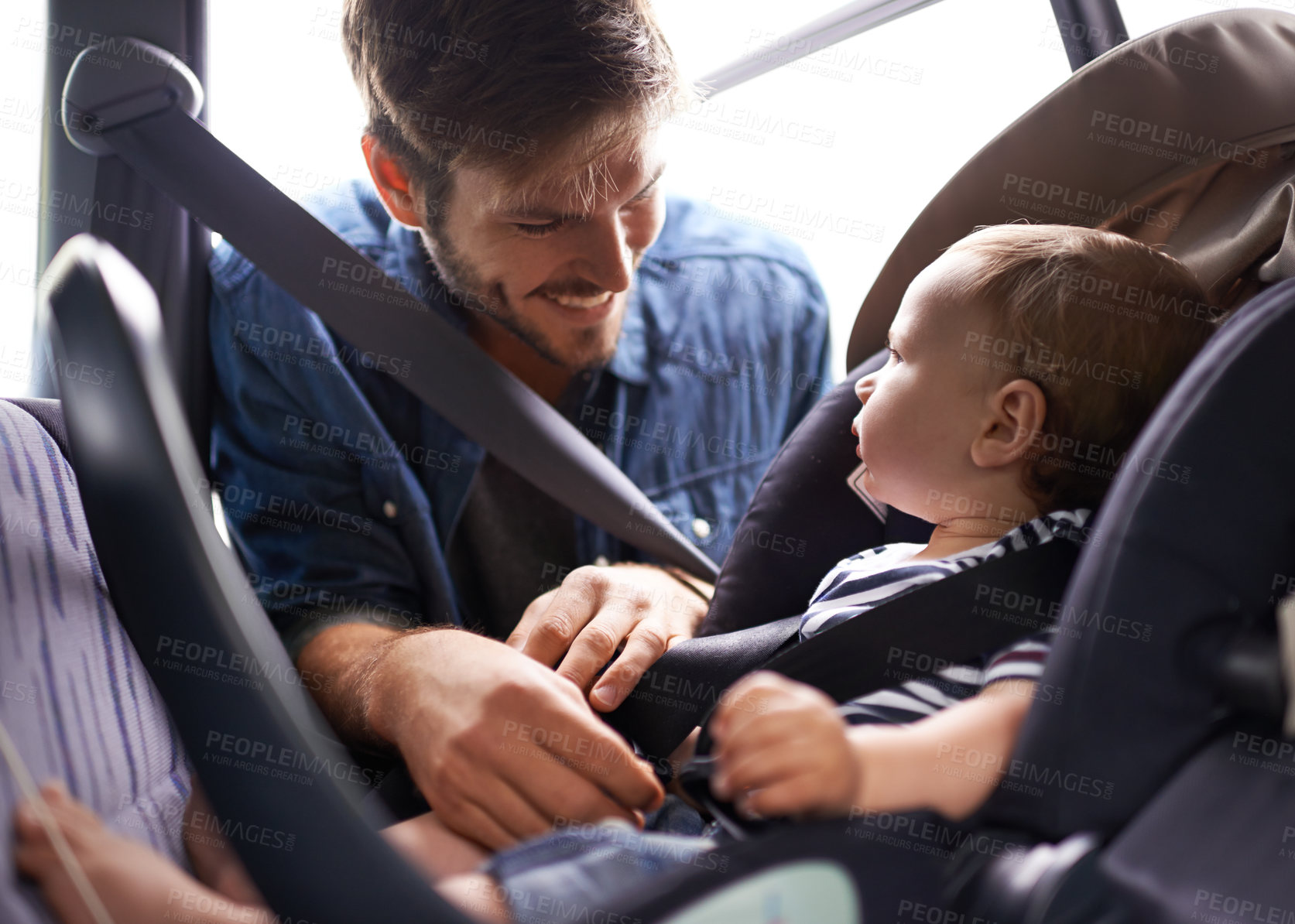 Buy stock photo A young father strapping his baby into a car seat