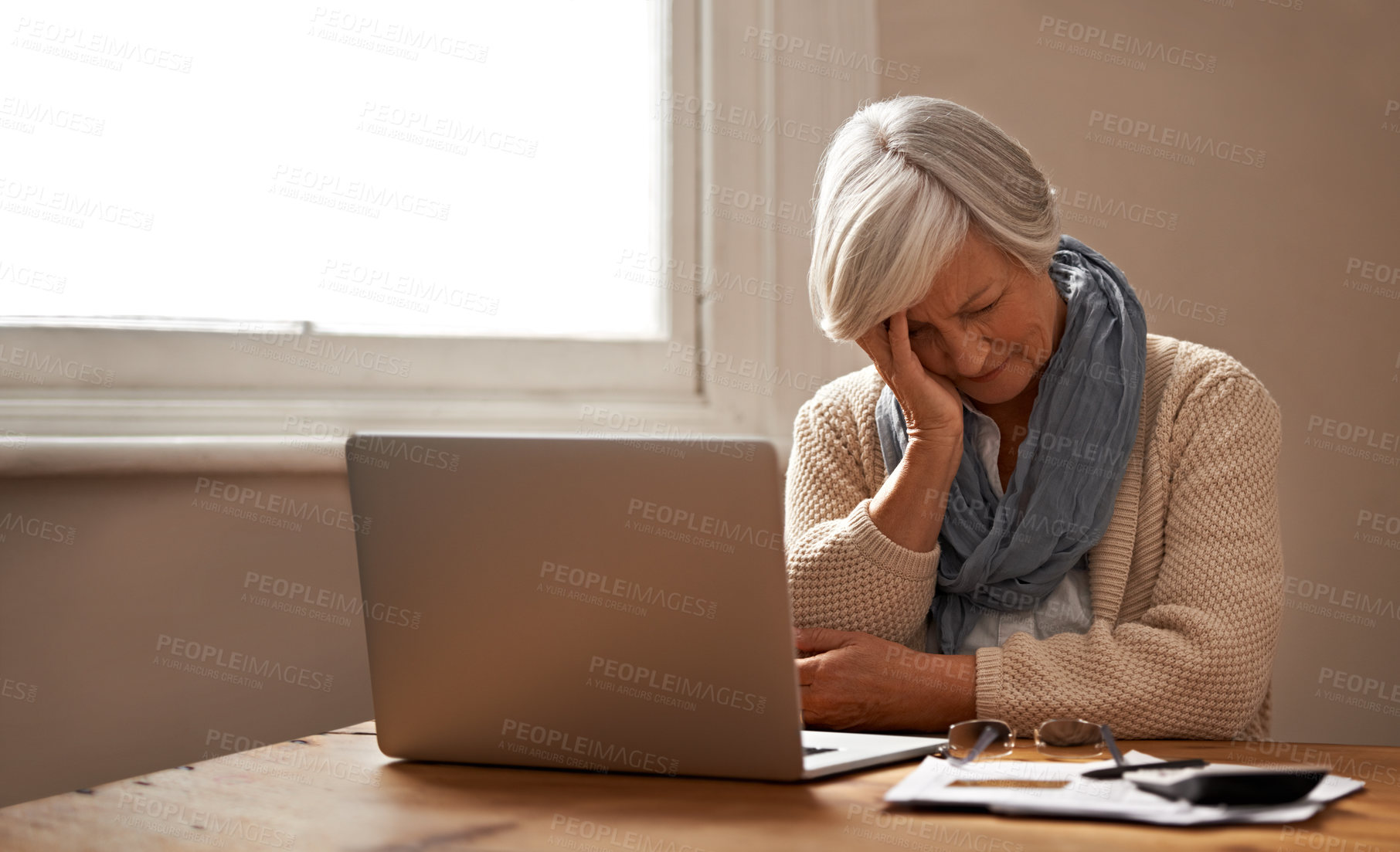 Buy stock photo An elederly woman sitting in front of her laptop looking stressed and worried
