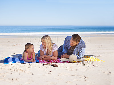 Buy stock photo Relax, smile and family at beach with blanket, sand and tropical holiday adventure together. Happy mother, father and daughter on ocean vacation with blue sky, sunshine and island at sea with girl