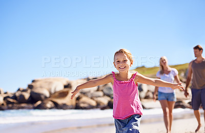 Buy stock photo A little girl running in front of her parents as they stroll on the beach