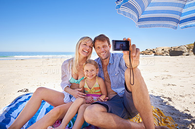 Buy stock photo Shot of a happy young family taking a photo of themselves at the beach