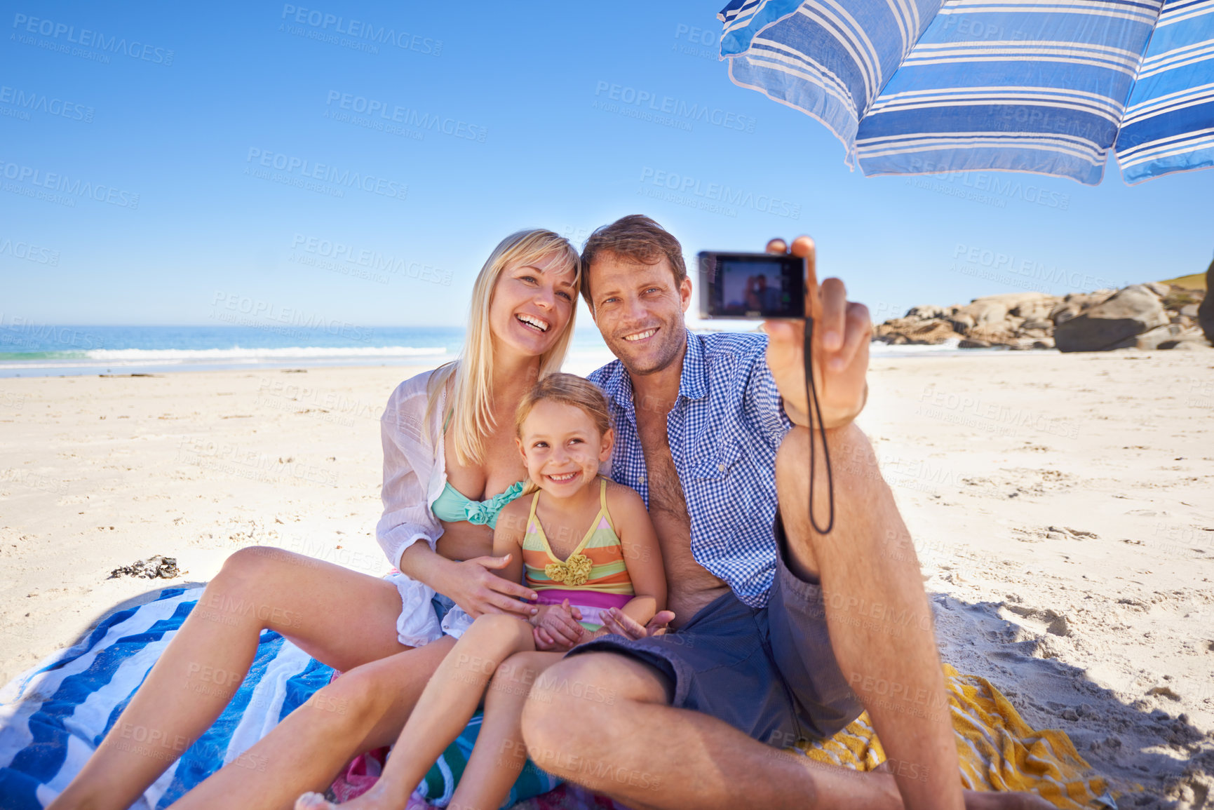Buy stock photo Shot of a happy young family taking a photo of themselves at the beach