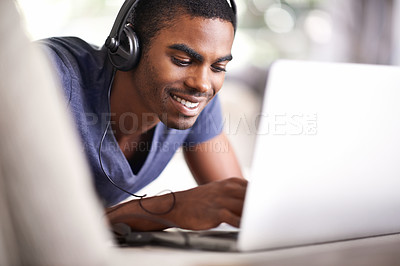 Buy stock photo Man, face and music with laptop in home for internet streaming, podcast and online research with smile. Student, black person and technology with headphones for relax, studying and learning on couch